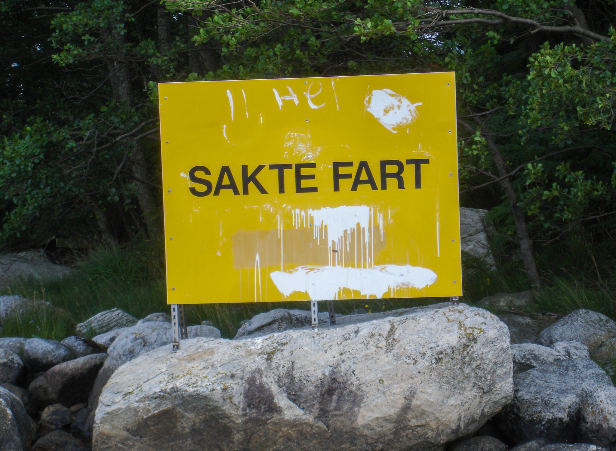 Det ene «sakte fart»-skiltet ved Erve står fortsatt, men er ramponert og har blitt forsøkt malt over. Skiltene oppfyller ikke dagens krav og skulle vært byttet innen utgangen av 2022. Foto: Privat