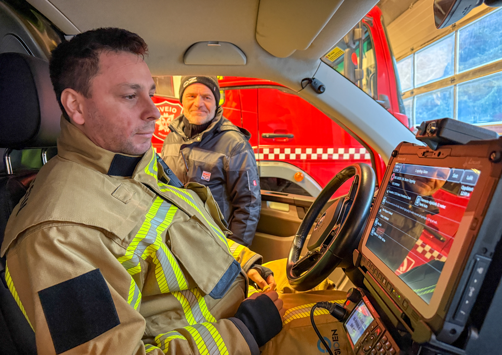 Med fastmontert skjerm i bilen har brannmannskapene fått en oppgradert versjon av kartsystemet Locus.Et verktøy som kan være avgjørende når alarmen går. Fra venstre: stasjonsmester ved Førde brannstasjon, Håkon Ureta Hansen, og brannkonstabel ved samme stasjon, Olav Magnar Hovland. Foto: Morten Vågset Møller